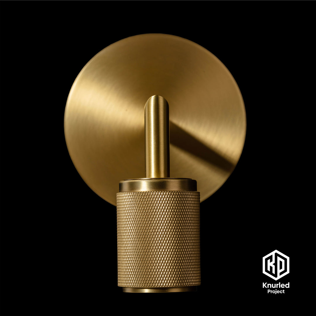 Brass wall light zoomed in to show diamond cut and knurled finish  on a black background