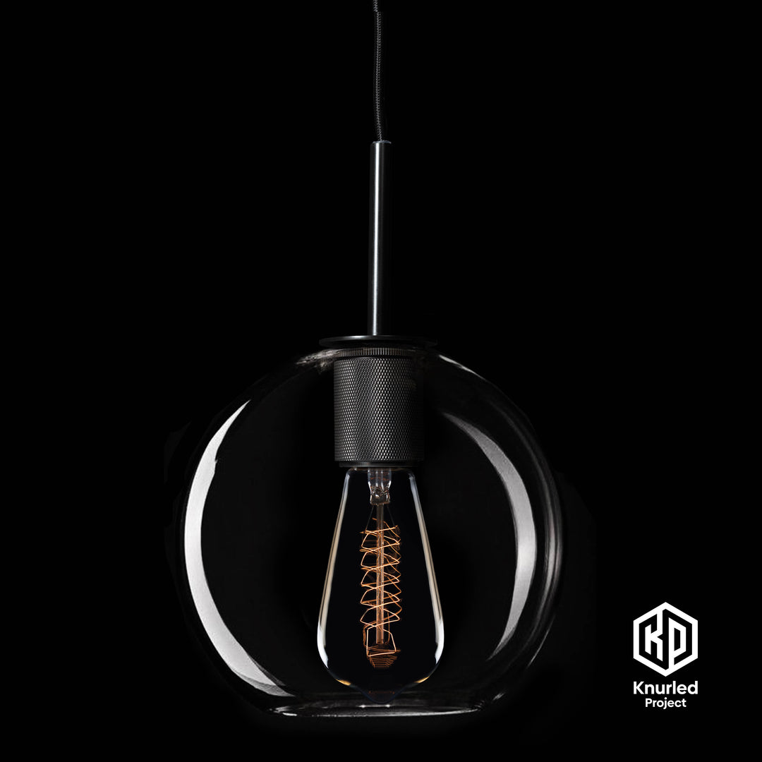 Matte black brass pendant light with filament bulb and globe shape light shade on a black background