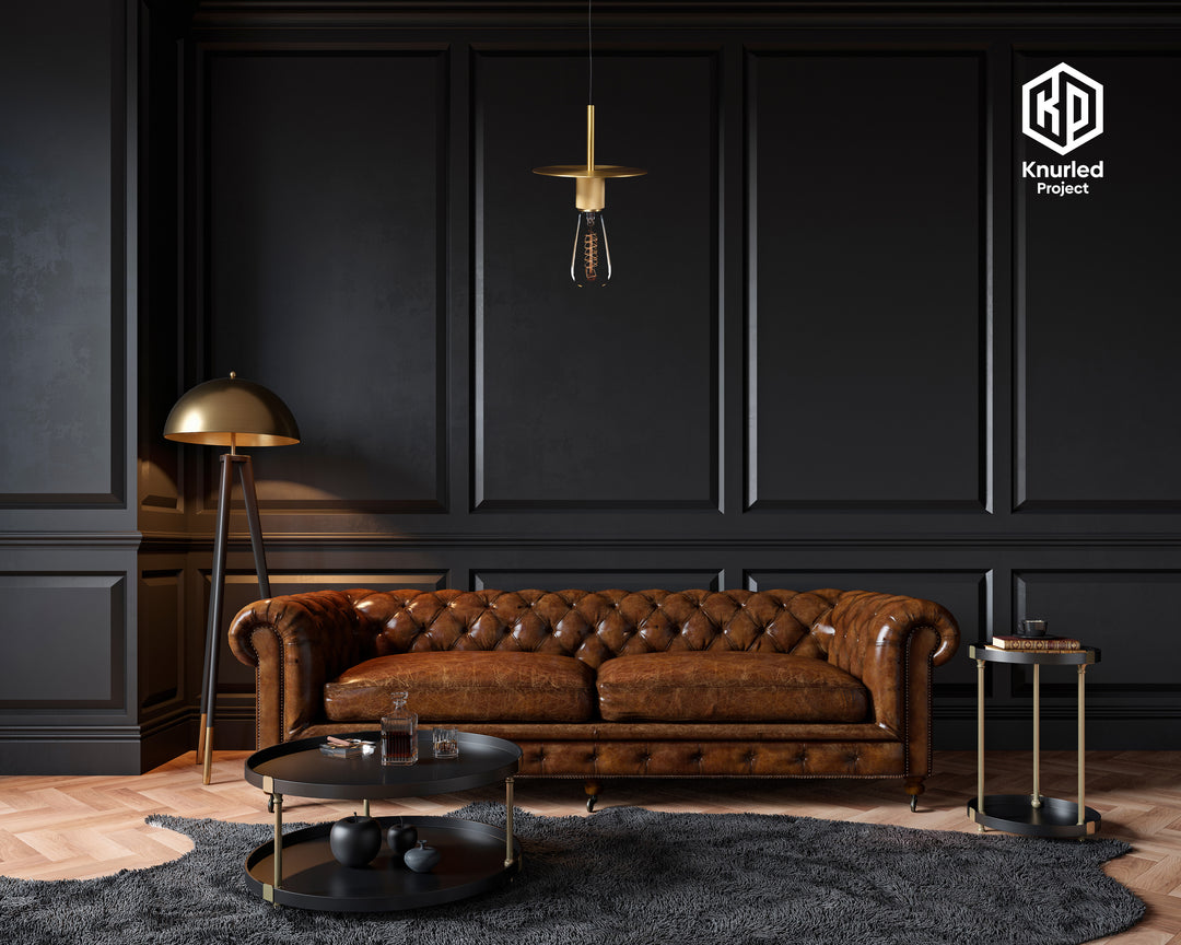 Brass pendant light hanging from a light chord with a filament bulb in a living room above a sofa and coffee table