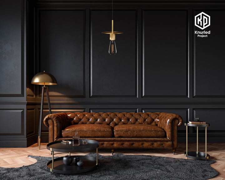 Brass pendant light hanging from a light chord with a filament bulb in a living room above a sofa and coffee table