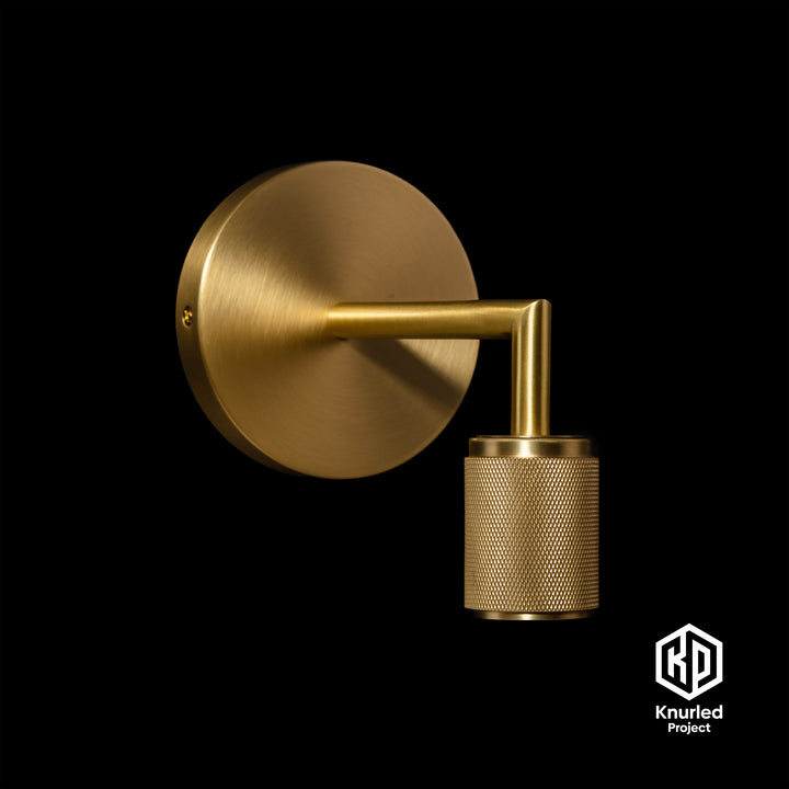 Brass wall light at an angle on a black background