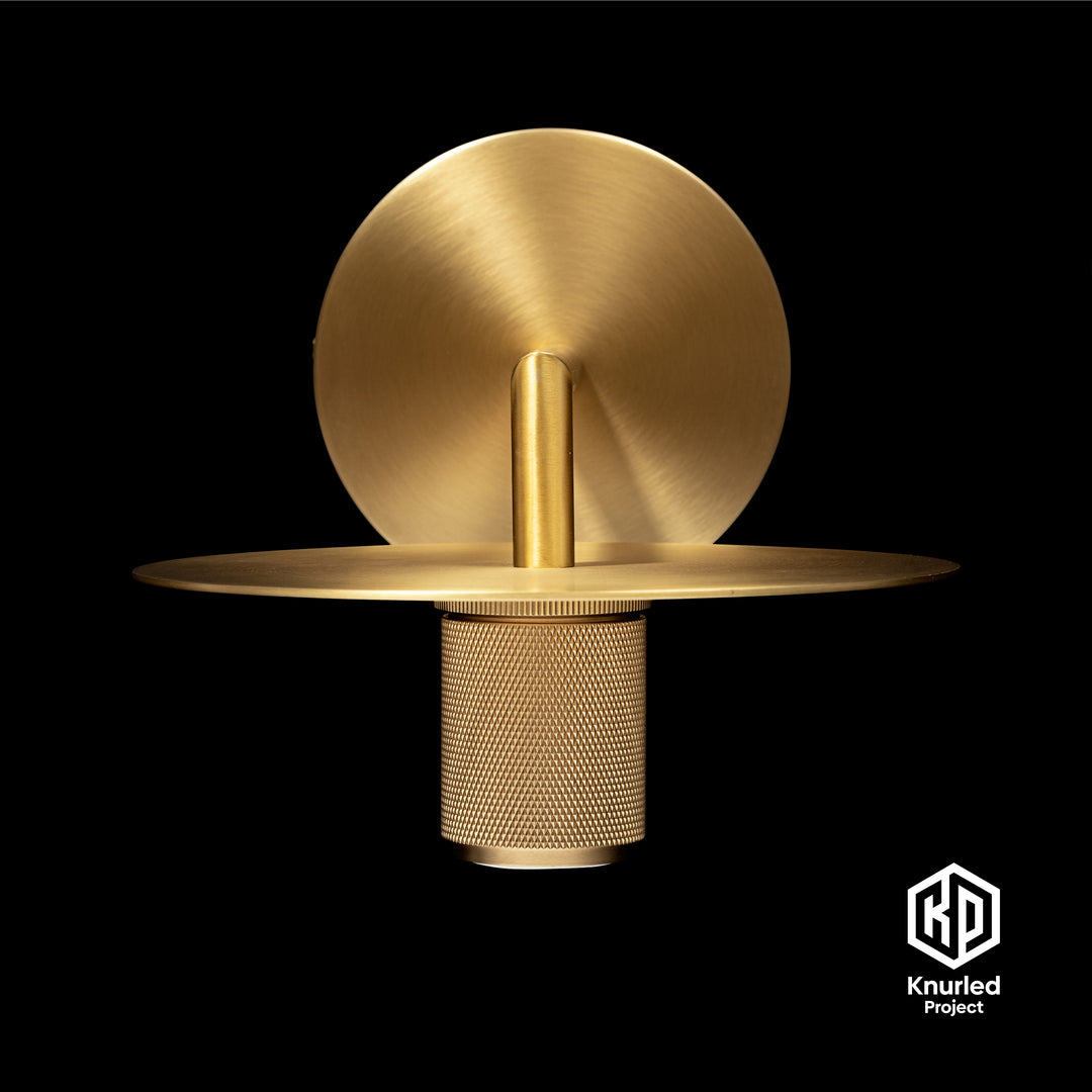 Brass wall light front on view to show diamond cut and knurled finish on a black background