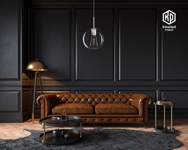 Chrome pendant light with filament bulb and a globe shaped light shade, hanging from a light chord  in a living room